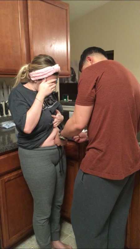 Husband injecting fertility medication into wife's stomach 