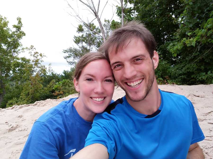 Couple who saved their first kiss for wedding day sit smiling on beach in selfie