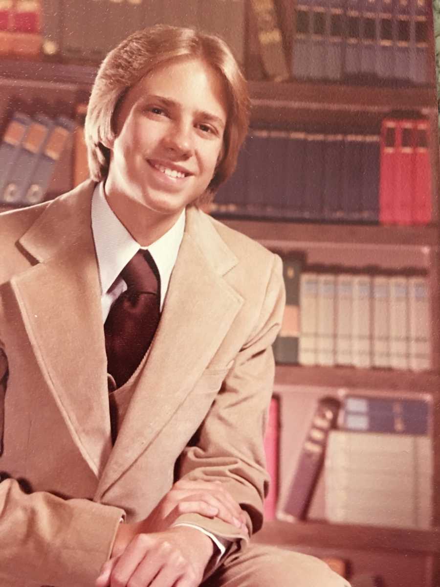 Young man sitting in suit in library who will later suffer from dementia and parkinson's