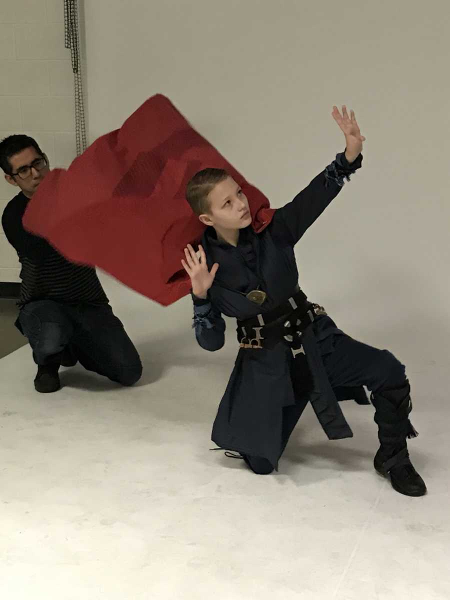 Young boy with cerebellar atrophy posing like Doctor Strange in his costume