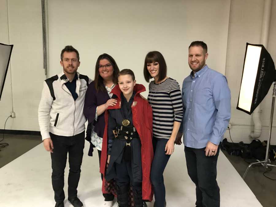 Boy with cerebellar atrophy at photo shoot in Doctor Strange costume beside parents and photgraphers