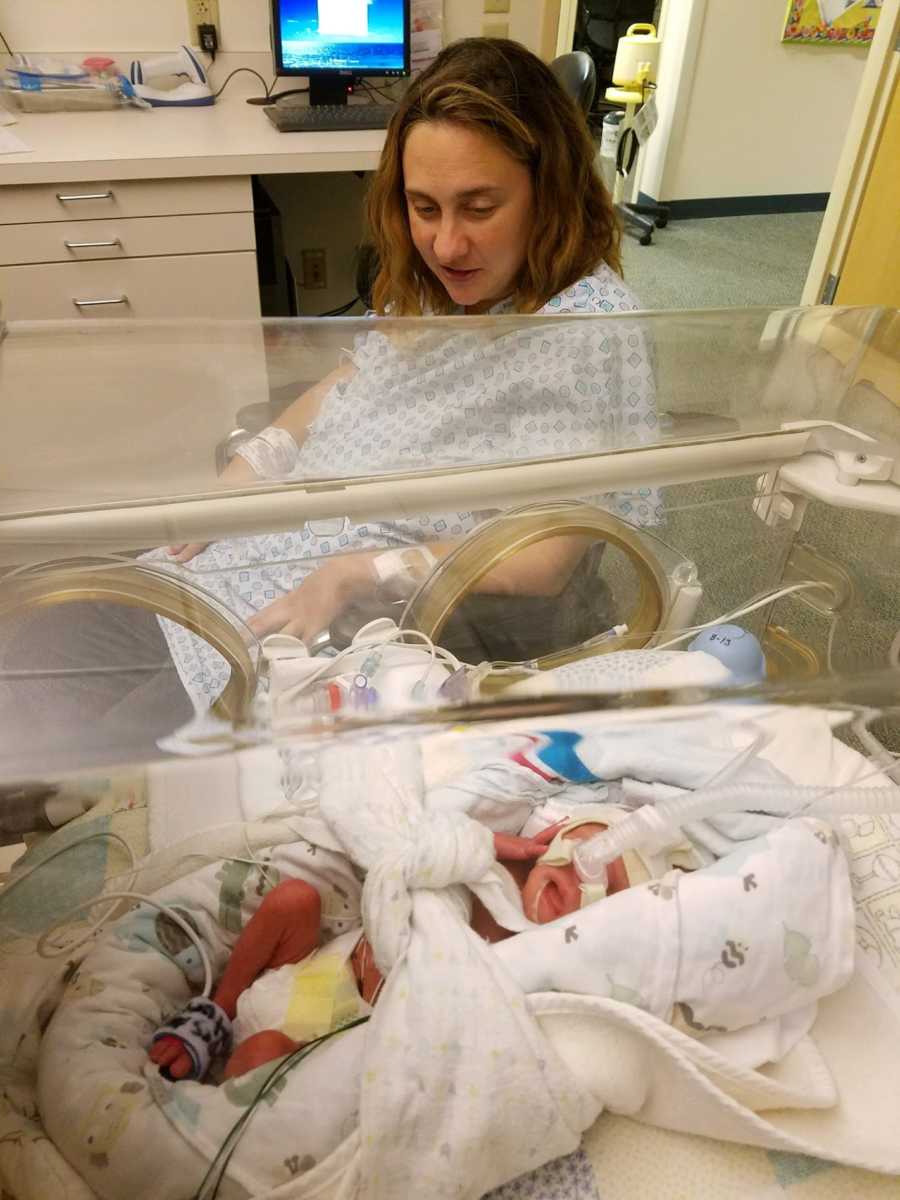 Mother who just gave birth looks over at newborn sleeping in NICU