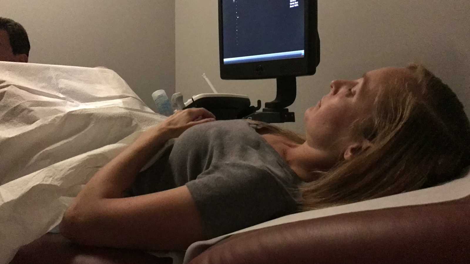 Woman lying on bed in doctor's office awaiting ultrasound after IVF treatment