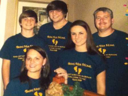 Husband and wife smile with three teen children after home invasion