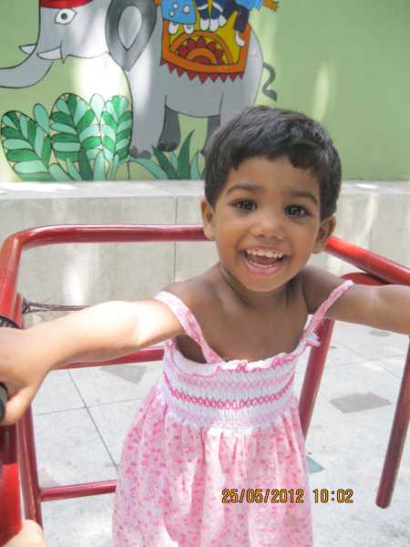 Young child in pink dress who will be adopted family whose home was invaded smiling 