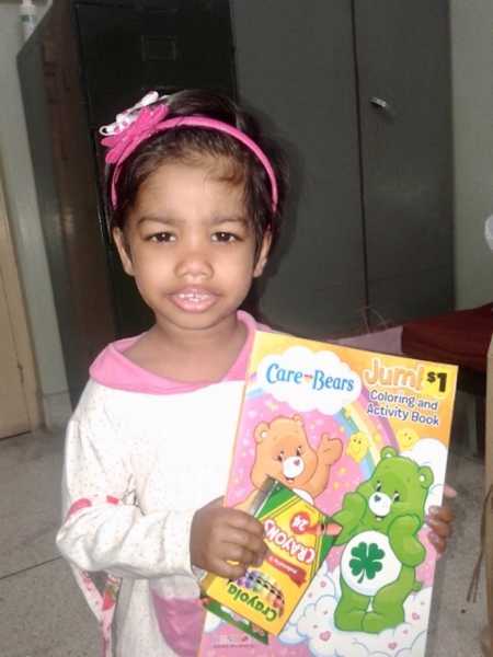 Adopted child holds crayons and care bear coloring book