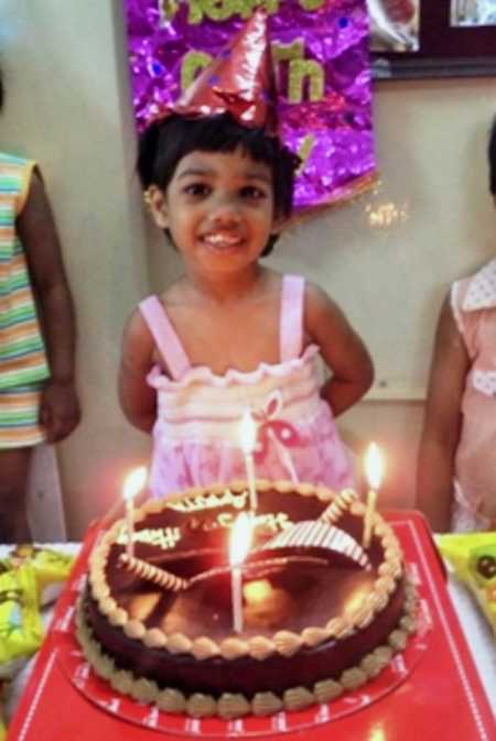 Young girl who was adopted smiles behind her birthday cake