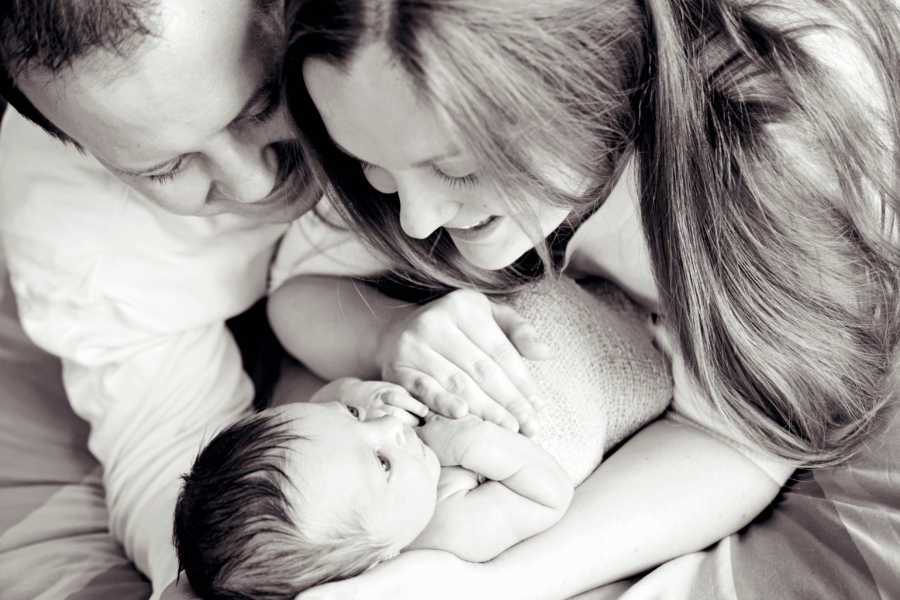 Newborn looks up at mother and father as they hold her in their arms