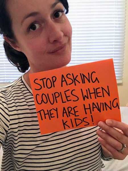 Woman holding up sign saying, "stop asking couples when they are having kids"