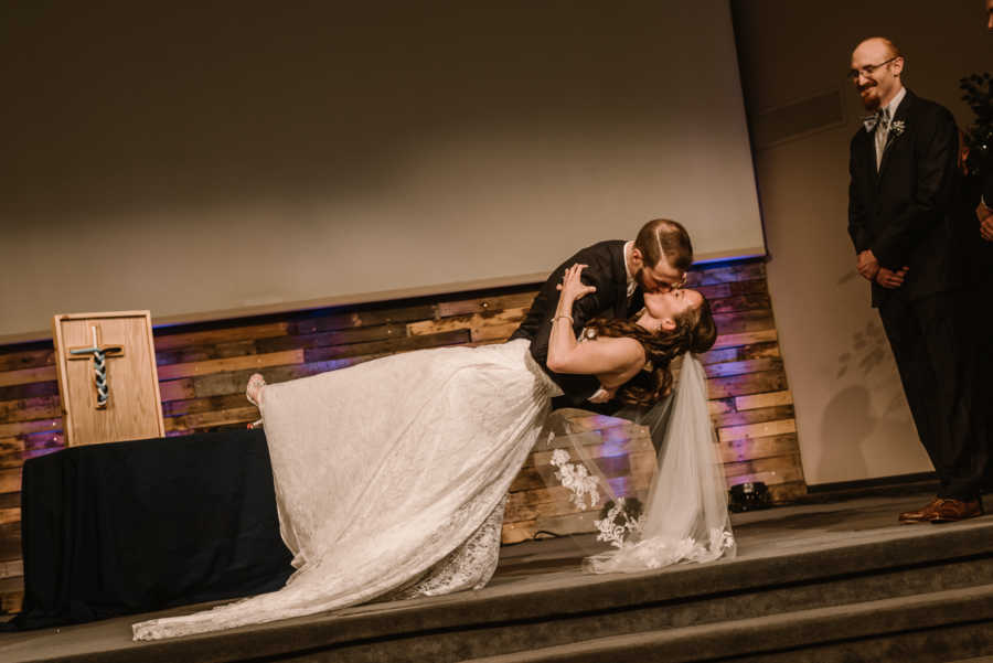 Groom dipping bride at wedding for their first kiss