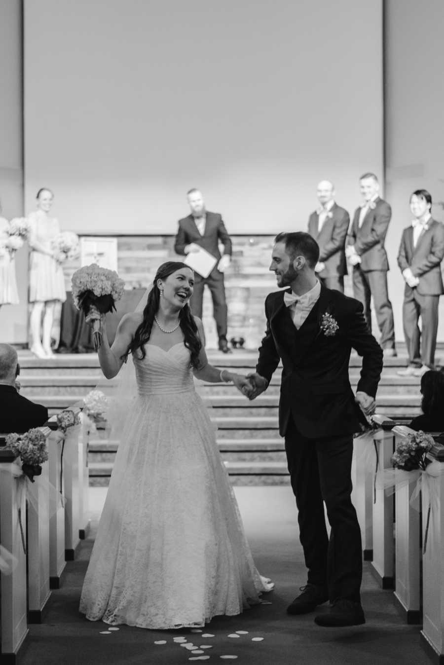 Bride and groom who saved first kiss for wedding walk down aisle smiling at each other