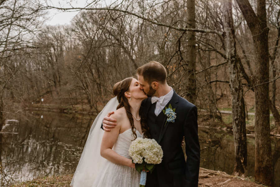Bride and groom kiss outside with river in background