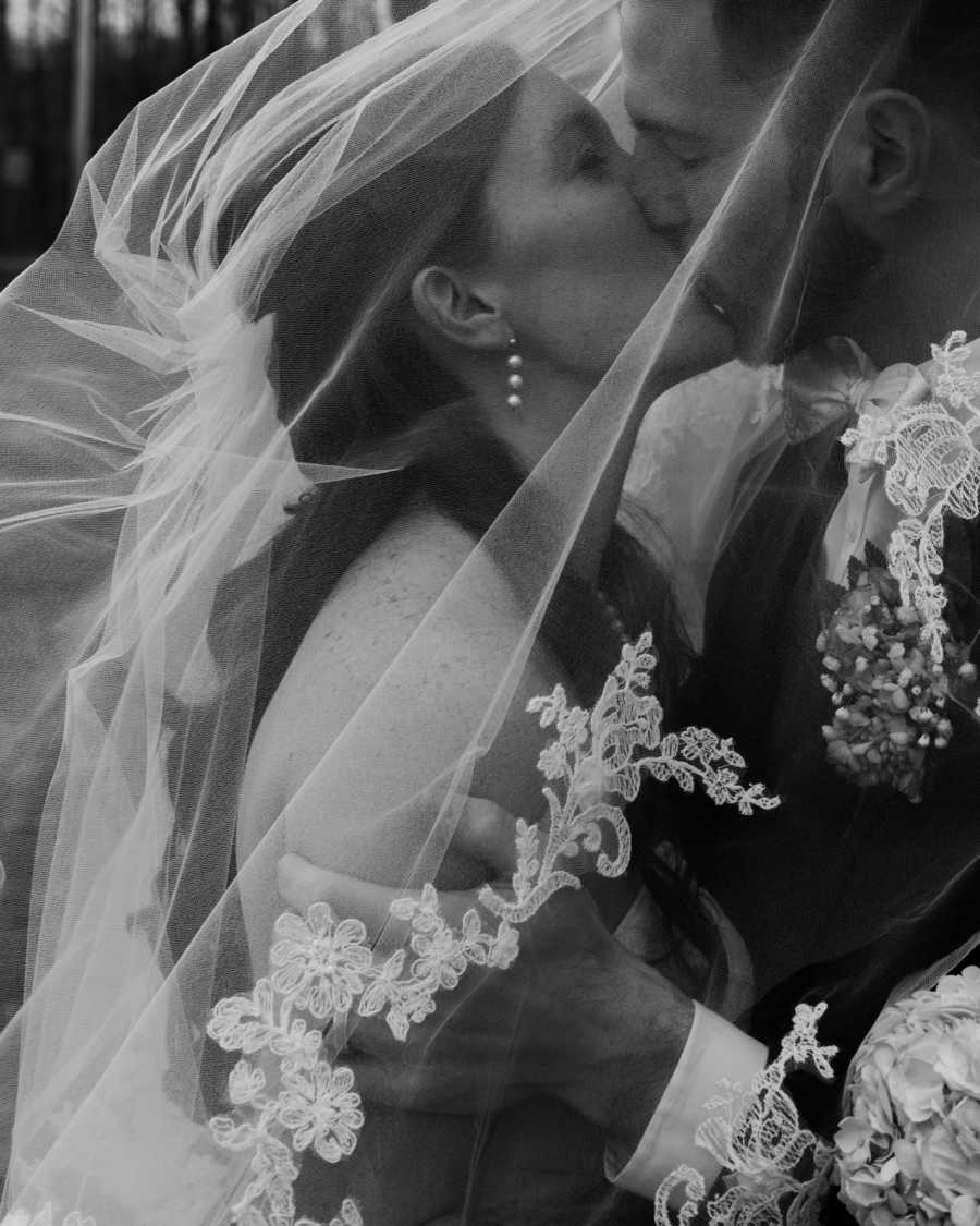 Bride and groom kiss under veil