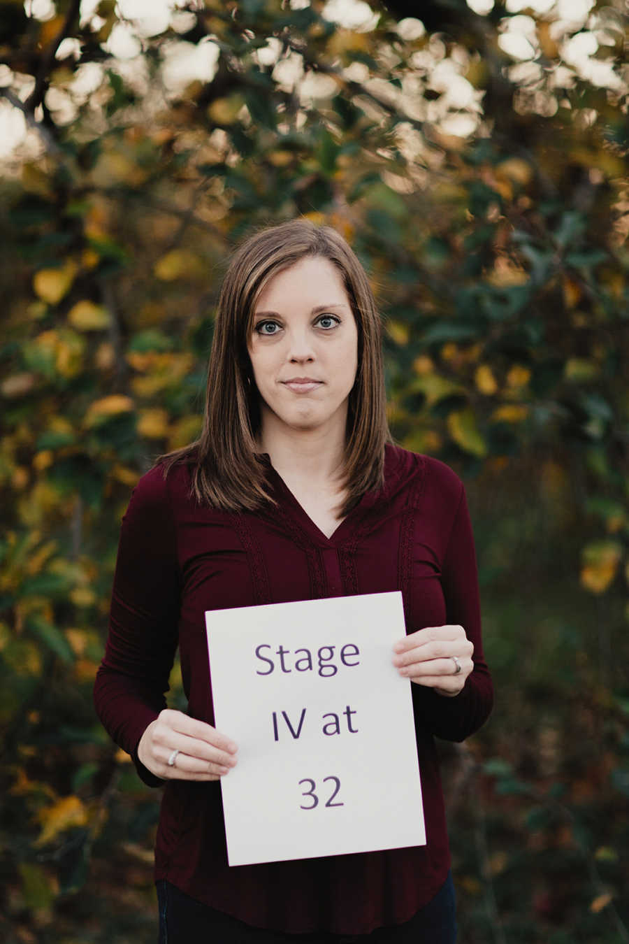 Young mother holding up sign saying, "stage IV at 32"