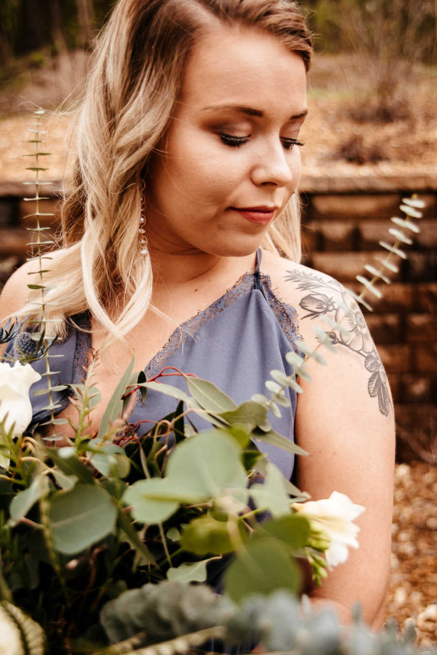 Close up of girlfriend looking down while holding bouquet of flowers