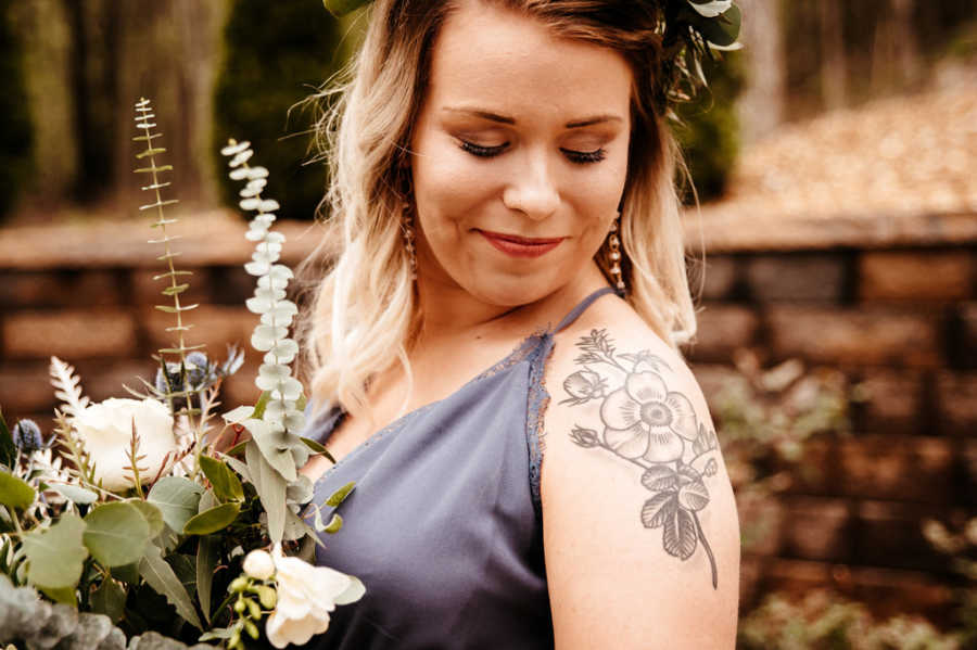 Woman stands looking over her shoulder holding bouquet of flowers