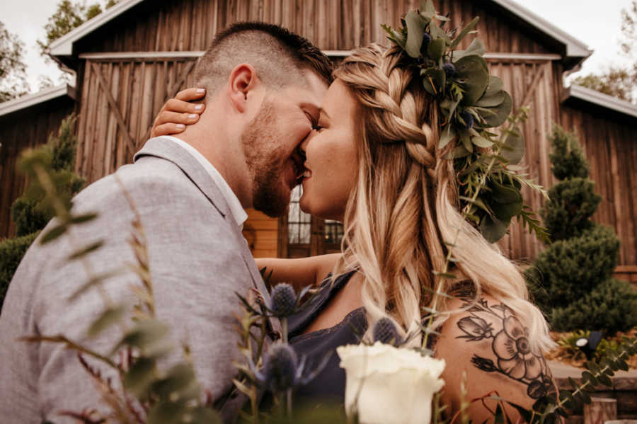 Boyfriend and girlfriend kiss in front of barn
