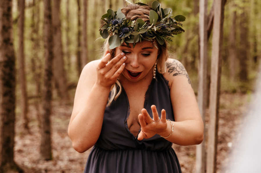 Woman wiping away tear while looking at engagement ring