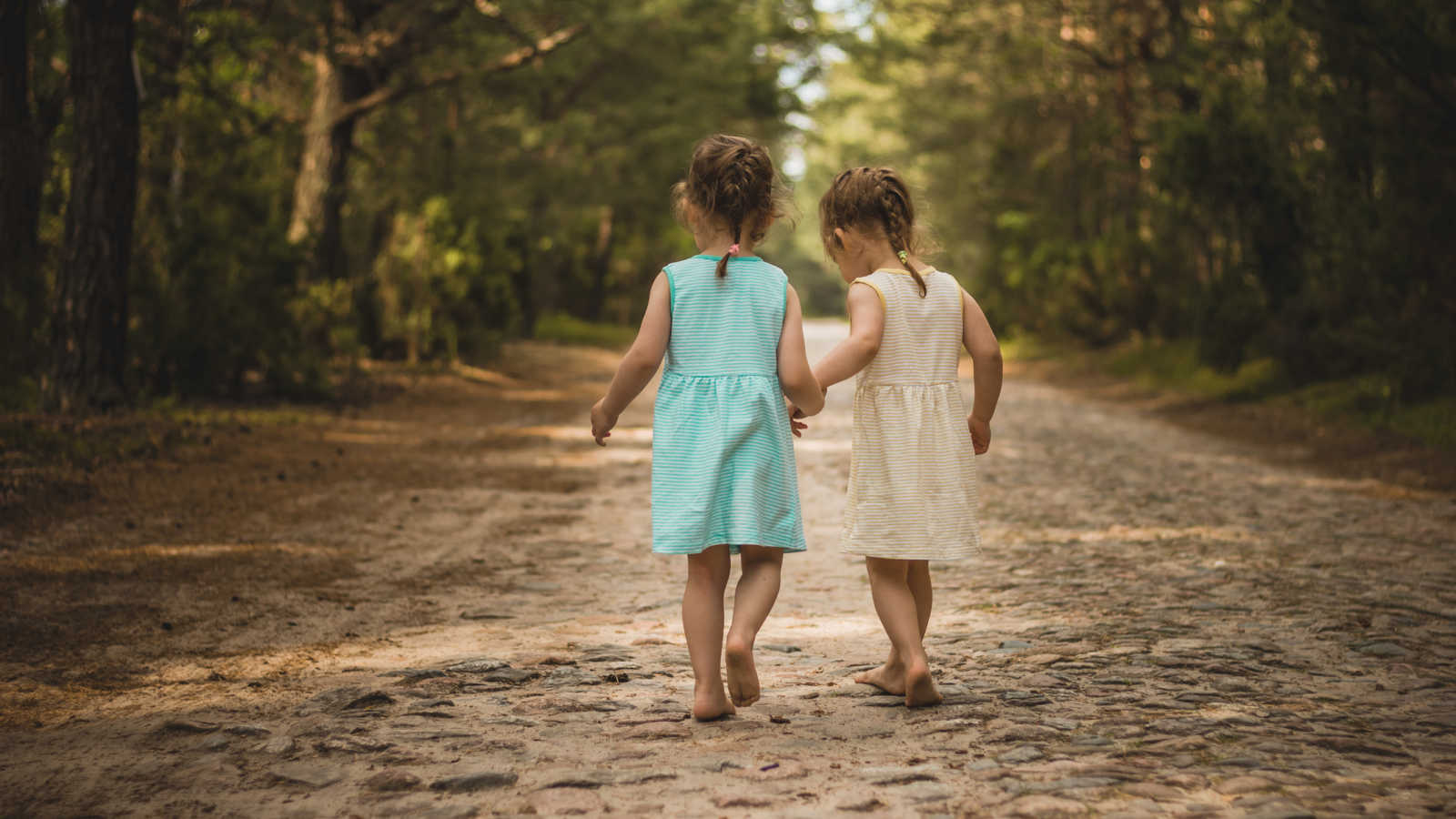 Twin toddler girls who weren't separated at foster home holding hands walking