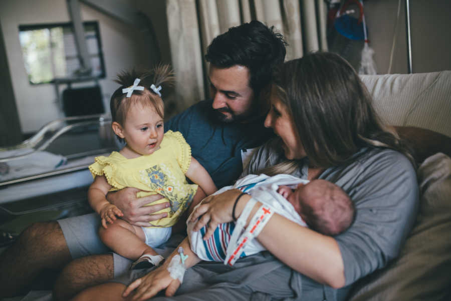 IVF baby smiles at newborn sister who is being held in mothers arms