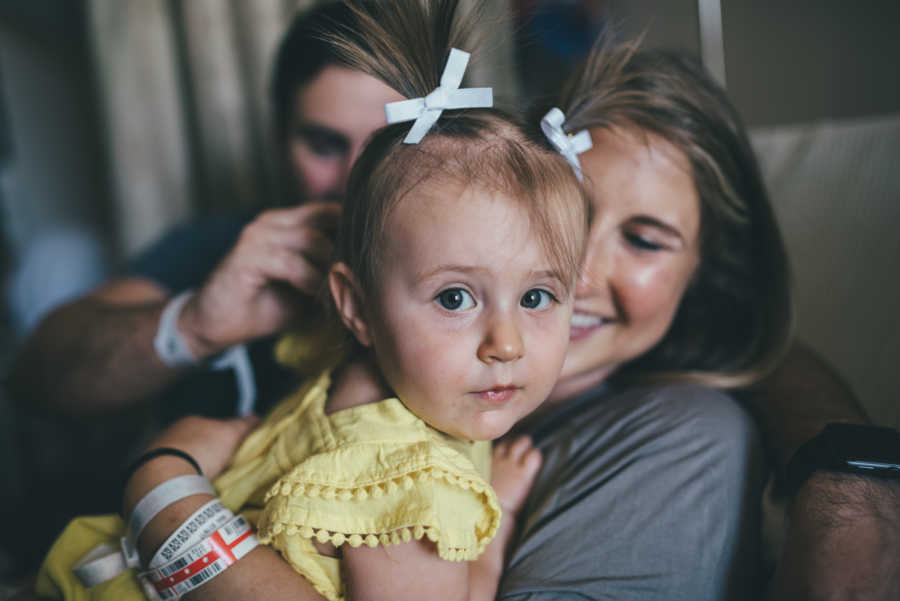 Mom smiles while holding firstborn who was conceived through IVF after giving birth to natural born daughter