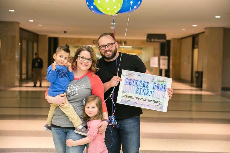 Mother and father stand in hospital with birth daughter and adopted son after he underwent surgery