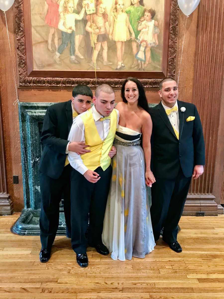 Woman smiles besides three brothers with autism 