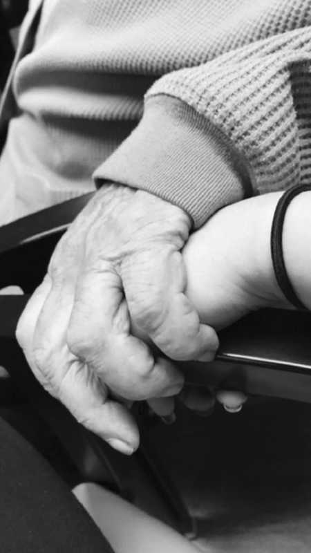 Elderly hand holding hand of assisted living employee