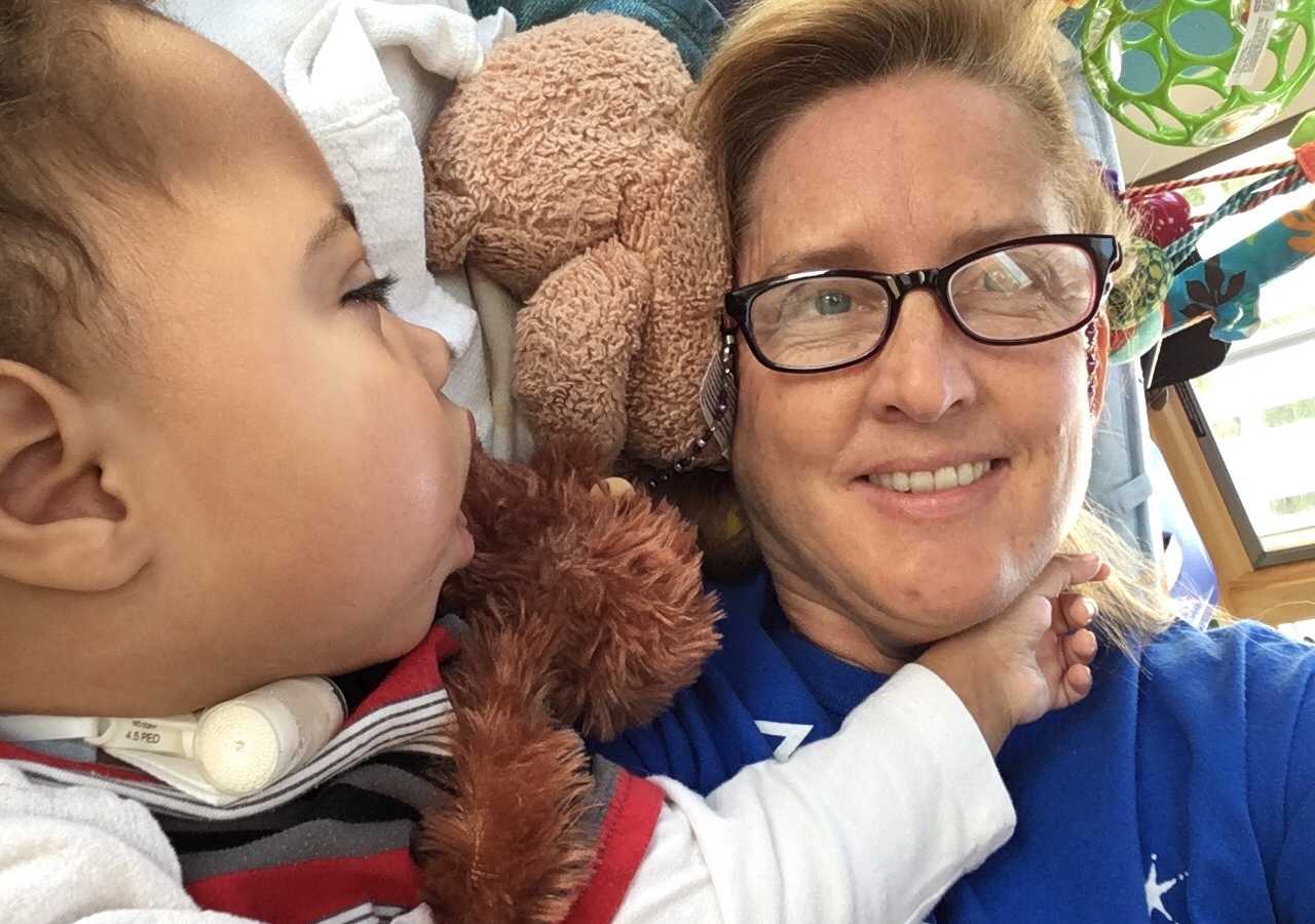 Woman lies in hospital bed with adopted son who is terminally ill