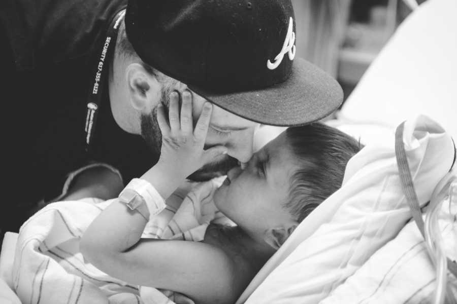 Father kisses adopted son who lies in hospital bed