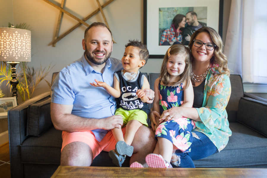 Mother and father sitting on couch with birth daughter and adopted son