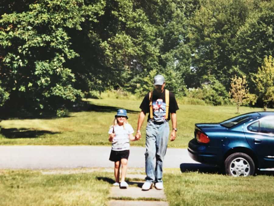 Father who will later in life suffer from dementia walks on sidewalk holding daughter's hand