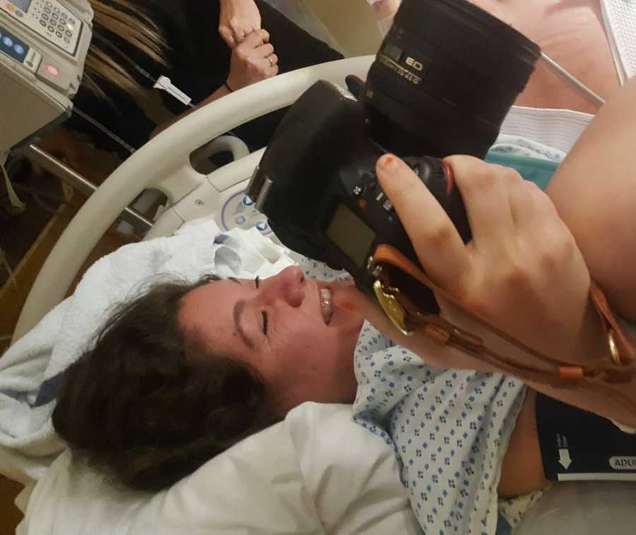 Woman giving birth holds camera to capture childbirth