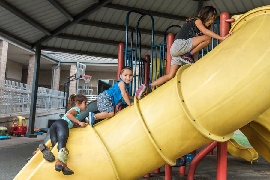 Children climb on top of slide at homeless shelter playground