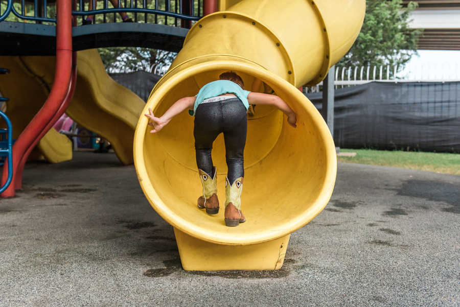 Daughter climbs up the inside of slide at homeless shelter