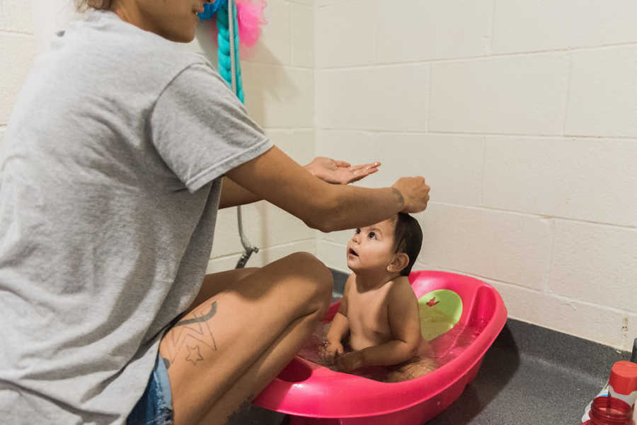 Mother gives baby daughter a bath in homeless shelter room