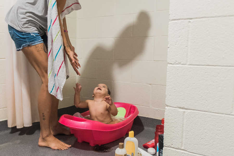 Baby in bath looks up at mom ready to get out in homeless shelter