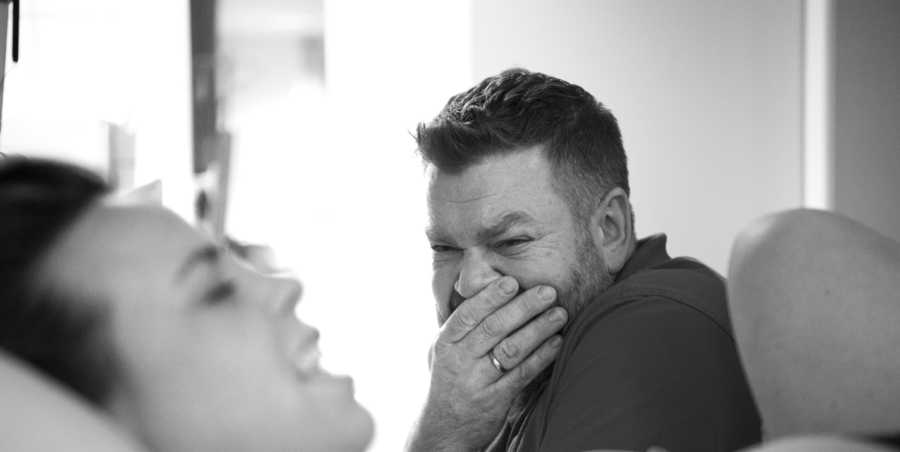 Husband holds hand over mouth crying while wife gives birth