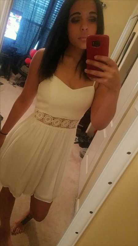 Teen who lost 155 pounds stands in white dress taking mirror selfie