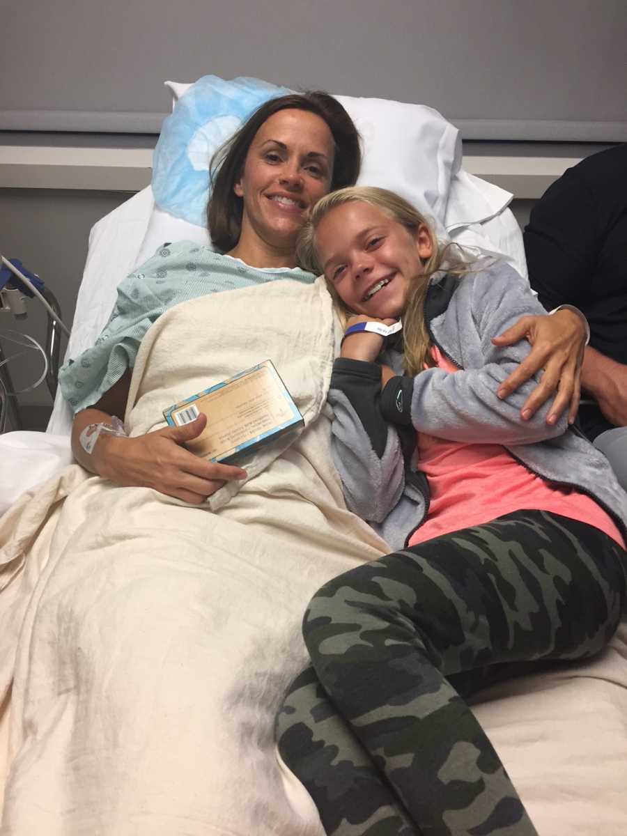 Woman who donated kidney to friend's husband lies in hospital bed with teen daughter smiling