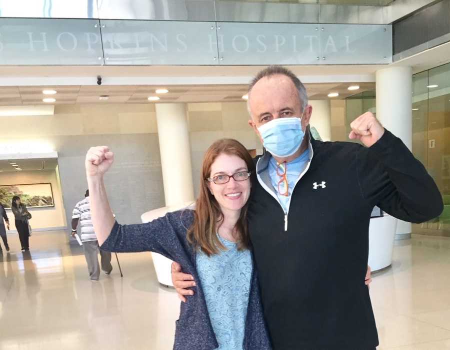 Man whose wife's friend donated her kidney to stands with his wife who are both flexing their muscles 