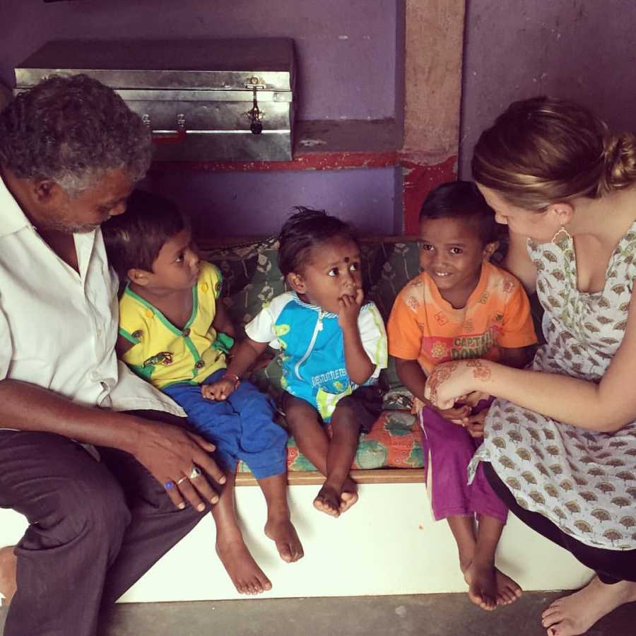 Woman sitting at orphanage in India with three little children and man 