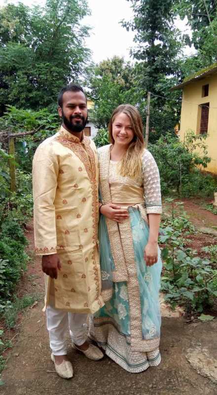 Husband and wife who will adopt a child from India, standing and smiling in traditional Indian clothing