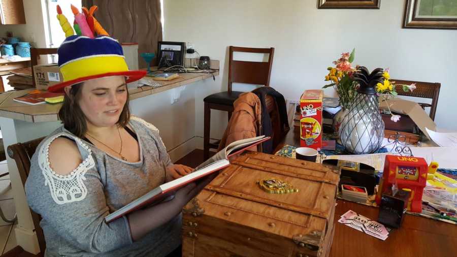 Girlfriend wearing birthday cake hat sitting at table with Harry Potter trunk boyfriend made for her