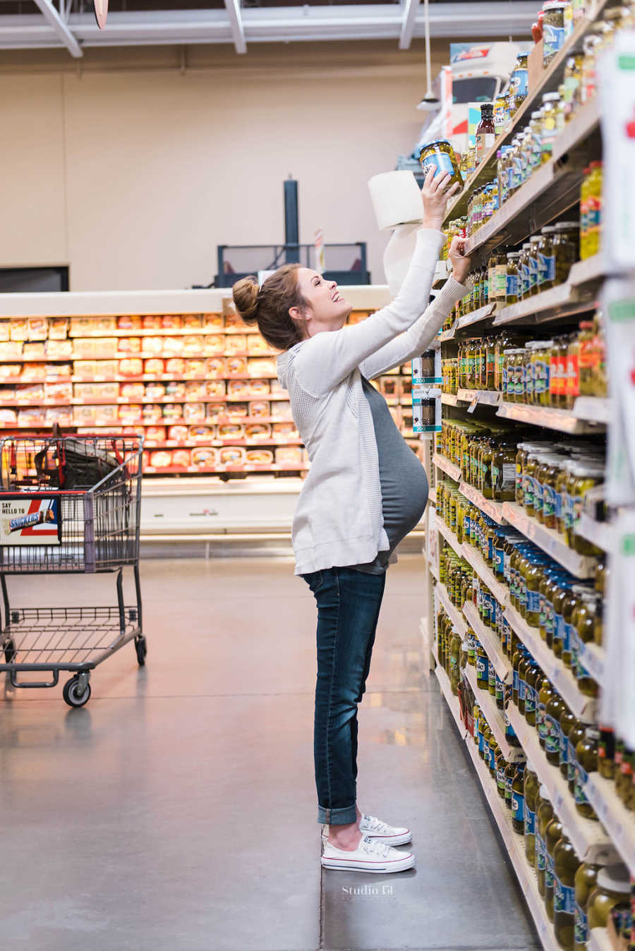Pregnant woman reaching for jar of pickles in grocery store