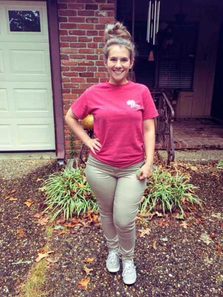 Young woman standing in front of her house smiling with hand on her hip