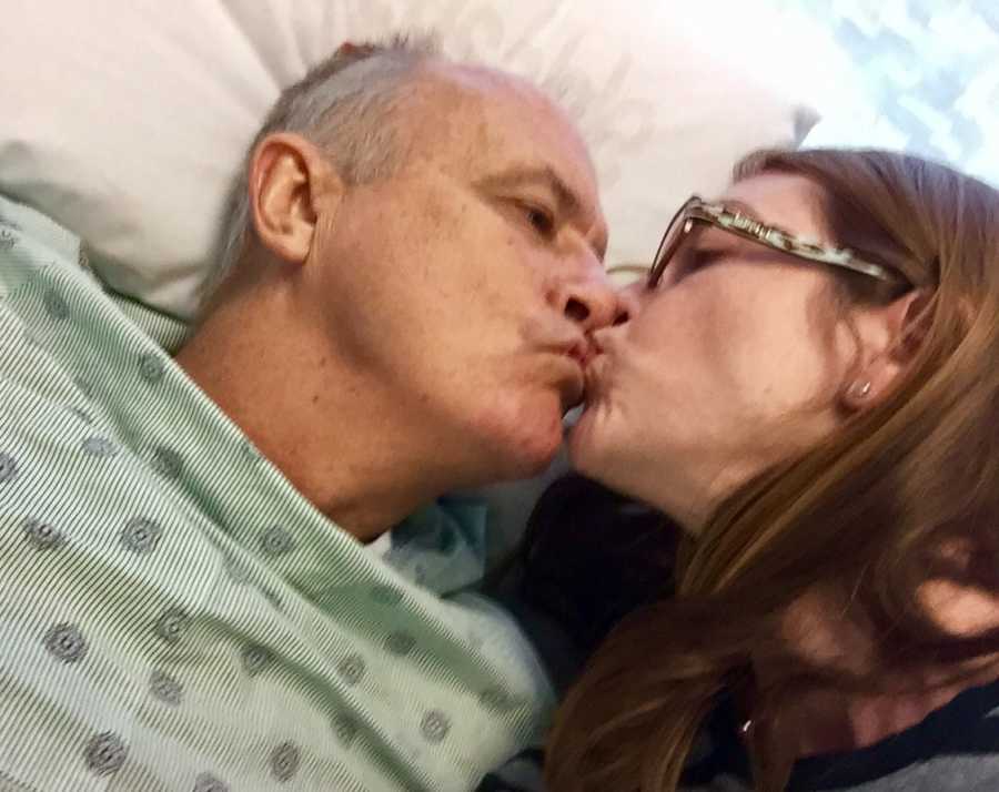 Close up of husband who needs kidney transplant lying in hospital bed kissing wife