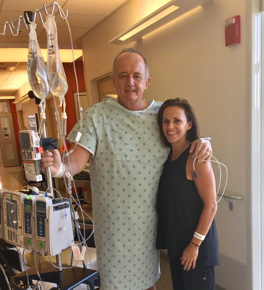 Man who received kidney from wife's friend stands in hospital gown with his donor