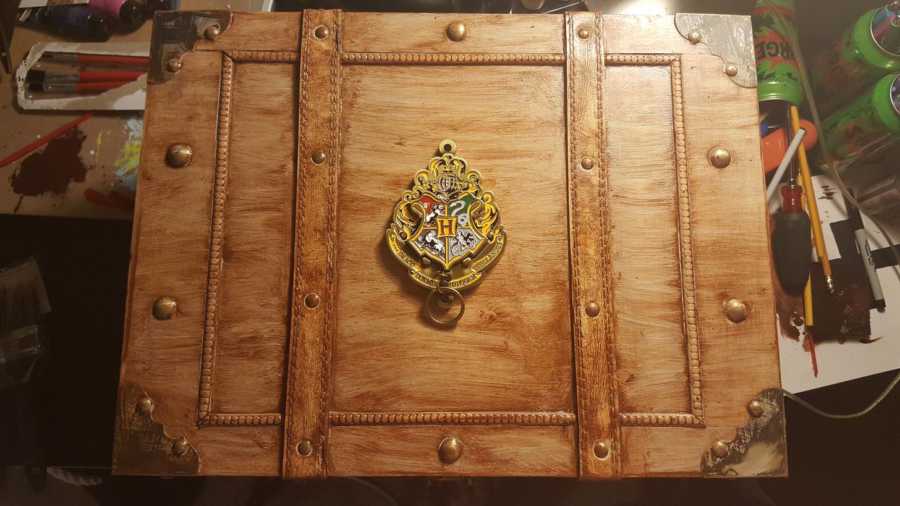Aerial view of keychain of Hogwarts crest placed on center of trunk