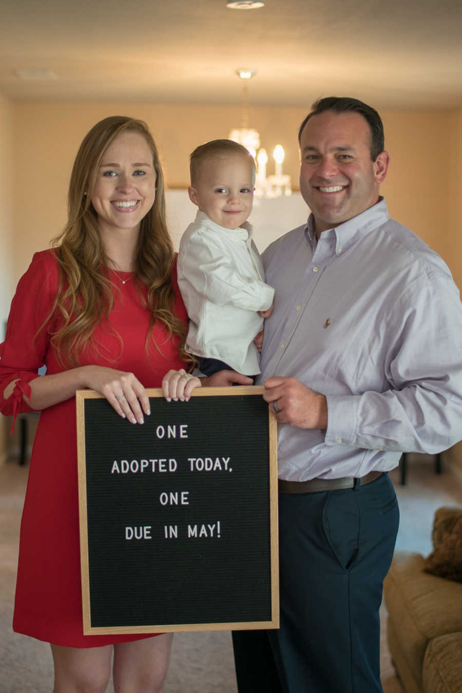 Husband and wife hold adopted son who is recovered from meth withdrawals and sign for baby announcement